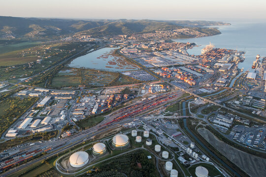 Aerial view of the Sermin industrial area and the Port of Koper, featuring large storage tanks, container terminals, and coastal infrastructure in Koper, Koper, Slovenia.