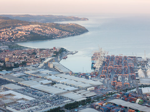 Aerial view of the Port of Koper and the Sermin industrial area with container terminals, cranes, and warehouses along the Adriatic coast in Koper, Slovenia.