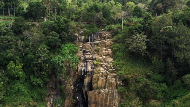 Aerial View of a Rocky Waterfall Cascading Through Lush Tropical Green