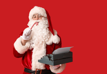 Obraz premium Santa Claus with vintage typewriter and candy cane on red background