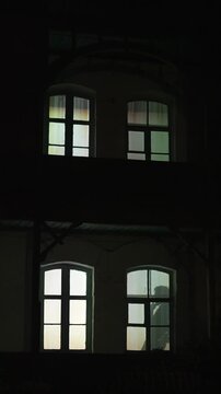 The silhouette of a lonely, sad man smoking cigarettes. The light in the window of the house in the evening 