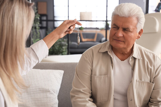 Hypnotherapy and mental health treatment, therapist using a pendulum to hypnotize a senior man for stress relief and psychological healing in a clinic