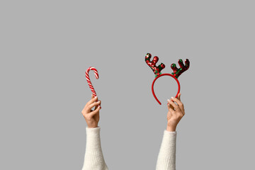 Female hands holding Christmas reindeer horns headband with candy cane on white background © Pixel-Shot