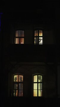 Couple Silhouette Drinking Wine by Window. Romantic dinner. Cozy Home with Warm Window Light