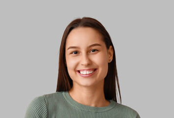Positive mindset and mental wellness, happy young woman smiling at camera for corporate headshot or social media profile portrait on gray background © Pixel-Shot