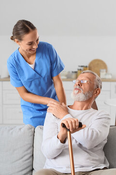 Elderly care and home health assistance, nurse supporting senior man with walking cane in living room for recovery and wellness support at home