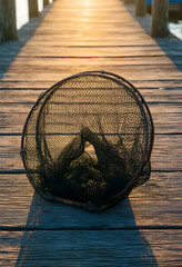 Fototapeta premium Fishing and leisure activity, landing net on a wooden pier at sunset for recreational angling and outdoor hobby lifestyle in a peaceful harbor setting