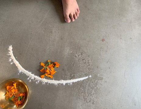 Unfinished Diwali rangoli, first rice-flour arc and loose marigold petals