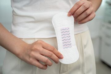 Asian woman holding sanitary napkin pad for hygiene menstrual period cycle protection. © manassanant