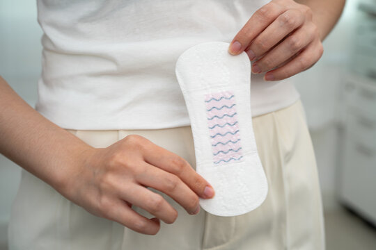 Asian woman holding sanitary napkin pad for hygiene menstrual period cycle protection.