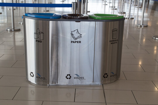 Stainless steel three-compartment waste recycling bin in airport terminal