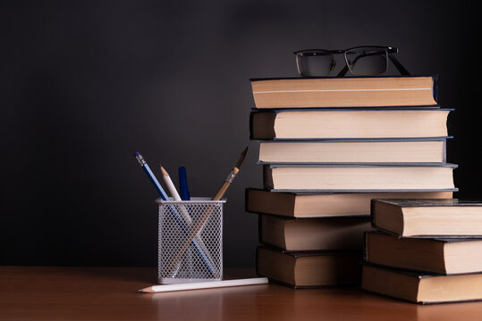 School blackboard with stack of books and pencils