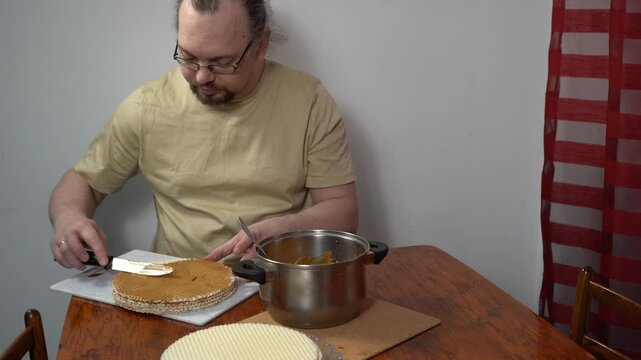 Man spreading waffle cakes with condensed milk. Make cake cream. Sweet food. Cooking
