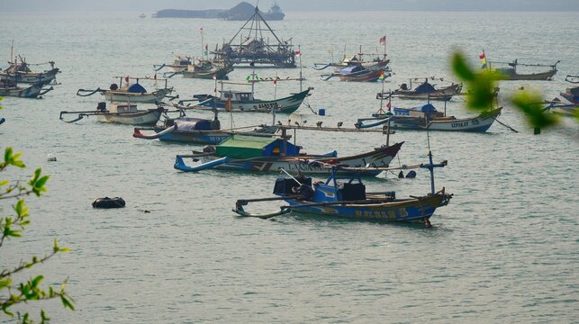 Palabuan Ratu Beach, Sukabumi, West Java, Indonesia, September 06, 2026 : Group of traditional Indonesian wooden outrigger fishing boats anchored in calm tropical sea waters
