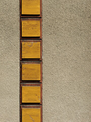 An unusual façade detailfeaturing vertically arranged yellow wooden panels set within a reddish-brown border against a rough-plastered facadecreates a striking contrast with plenty of open space. © Frank