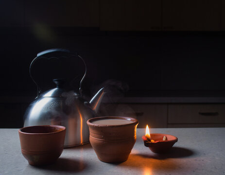 Chai steam and a single new diya on a pre-dawn Diwali kitchen counter