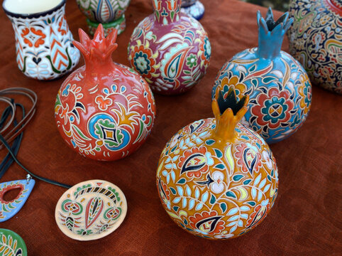 Handmade crimean tatar ceramic pomegranate figurines and souvenirs with colorful traditional patterns on textured fabric