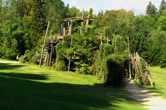 Borgo Valsugana, Italy - August 15, 2026: Visitors walking on a path near the artwork "Trabucco di montagna" (Mountain Trabucco) by artist Arne Quinze, in Arte Sella open-air contemporary art park
