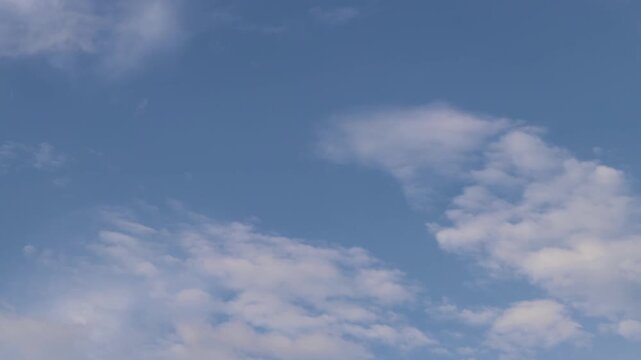 Sky with thin light white clouds in the daytime, natural background, space, height. Clear blue sky with thin, scattered white clouds. Minimalist landscape. View from below on a natural blue sky