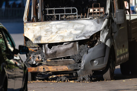 Burned small truck parked on a city street after fire front view close up
