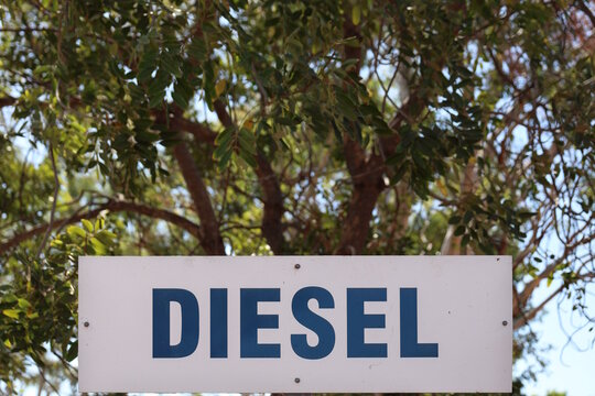 White diesel fuel sign mounted under green trees at a remote Australian Outback roadhouse serving travelers on an epic big lap road trip. Blurred background for copy space
