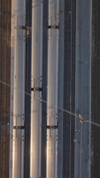 Vertical video: Aerial perspective capturing passenger trains parked in a bustling New York City rail station, neighboring stationary train on parallel tracks