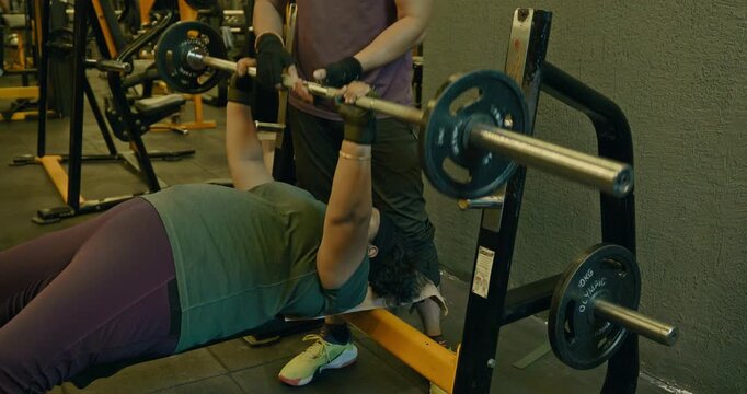 Fitness Athlete Performing Bench Press With Trainer Coaching and Support &mdash; Determined man completes chest workout sets using a bench press and rope exercise while a personal trainer provides guidance 