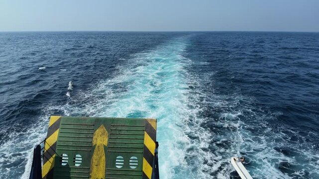 A view from the back of a ferry boat crossing the open ocean, showcasing deep blue sea water, foamy white wake, motion, travel, and adventure, perfect for vacation and maritime themes
