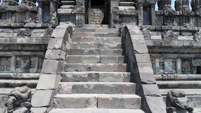 Ancient stone staircase leading to Prambanan temple entrance featuring intricate Hindu bas-relief carvings and weathered volcanic rock texture for cultural travel and historical heritage documentary
