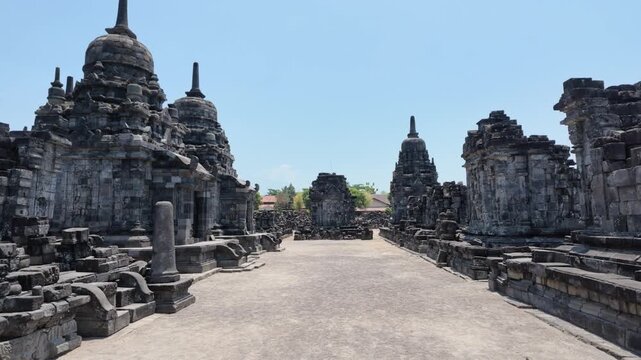 Ancient stone temple complex at Prambanan, Indonesia featuring towering historic architecture, weathered volcanic rock textures, traditional religious sanctuary, archaeological heritage site travel