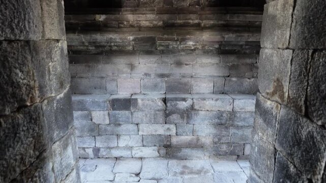 Ancient stone temple interior with weathered basalt blocks at Prambanan, weathered textures, historical architecture, detailed masonry, monumental atmosphere, spiritual heritage site, cultural travel