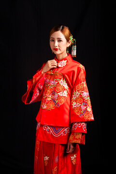 Bridal look featuring traditional Chinese red wedding attire against a black background.