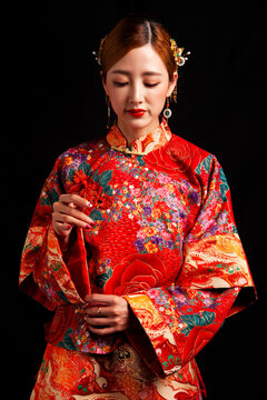 Bridal look featuring traditional Chinese red wedding attire against a black background.