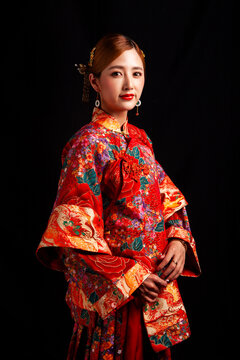 Bridal look featuring traditional Chinese red wedding attire against a black background.