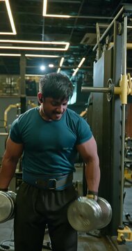 Bodybuilder Performing Intense Biceps Workout With Weights, Barbell and Rope in Gym &mdash; Muscular male athlete performs controlled biceps exercises using free weights, barbell and cable rope equipment. T