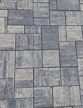 Grey concrete paving slab texture background, modern interlocking pavement pattern close-up with copy space