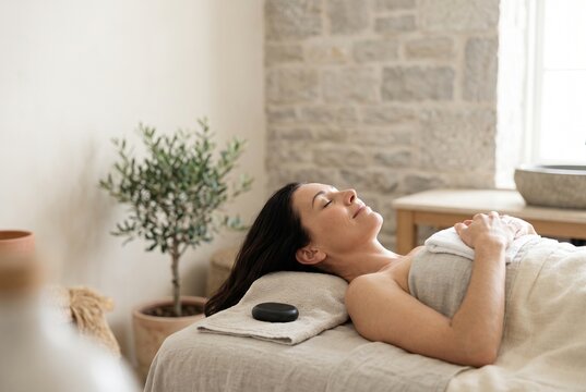 Woman relaxing on a spa treatment bed at a resort wellness retreat, representing self care, luxury travel, deep relaxation and peaceful holiday rejuvenation