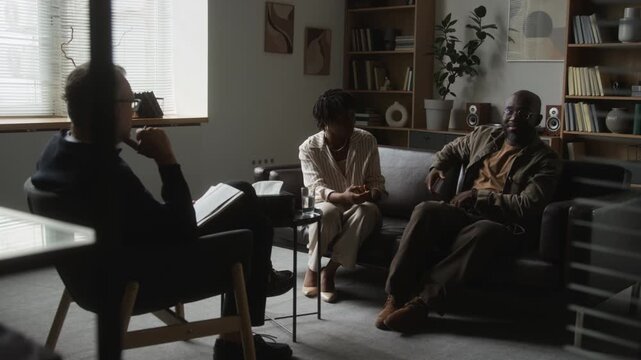 African American couple discussing marriage problems with middle aged Caucasian psychologist during therapy session. Footage suitable for mental health campaigns and marriage counseling promotions