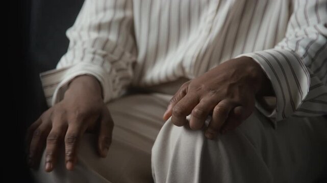 African American woman tapping nervous trembling fingers on knee showing anxiety symptoms. Clip suitable for healthcare campaigns focusing on neurology, Parkinson disease, mental health