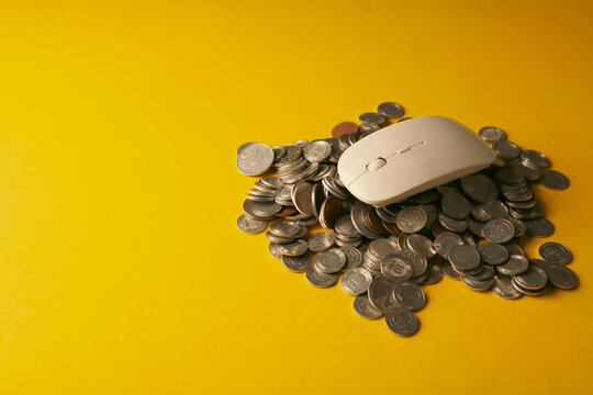 White computer mouse with gold coins on yellow background