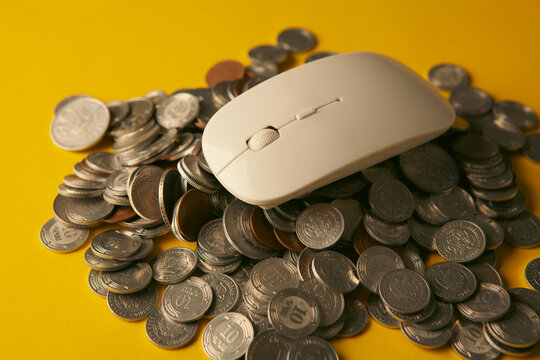 White computer mouse with gold coins on yellow background