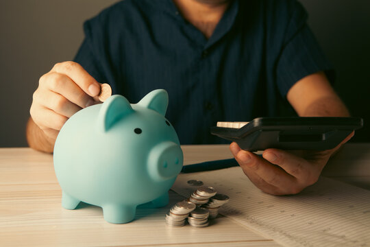 young man putting coin in piggy bank
