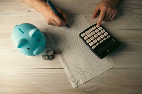 young man putting coin in piggy bank