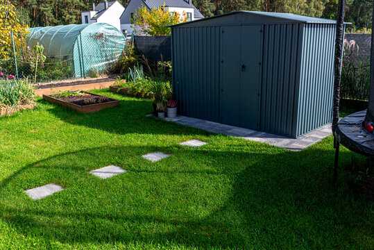 Backyard garden with shed, greenhouse and stepping stones