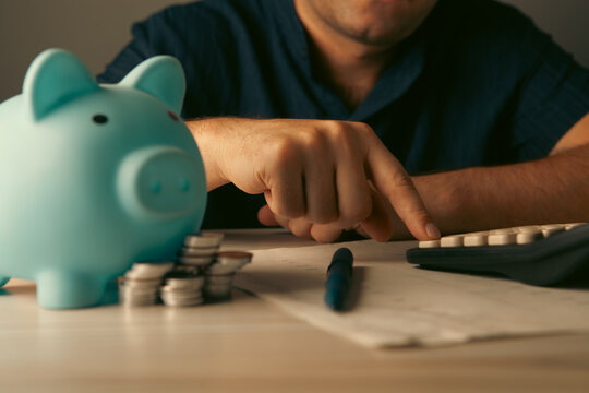young man putting coin in piggy bank