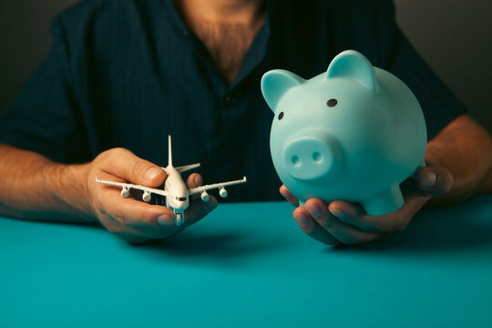 A piggy bank and an airplane in a person's hand.