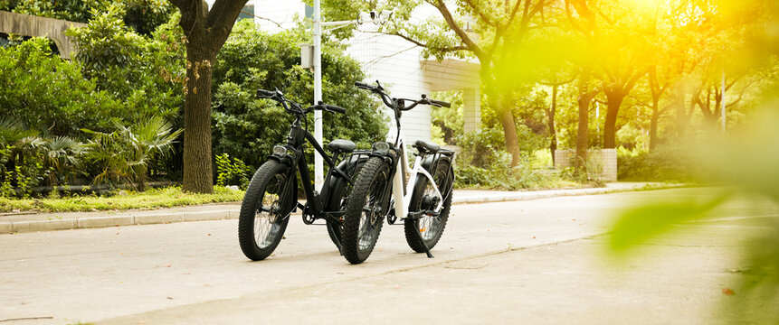 Sunset Park scene featuring two fat-tire e-bikes; showcasing an all-terrain e-bike urban commuting lifestyle.
