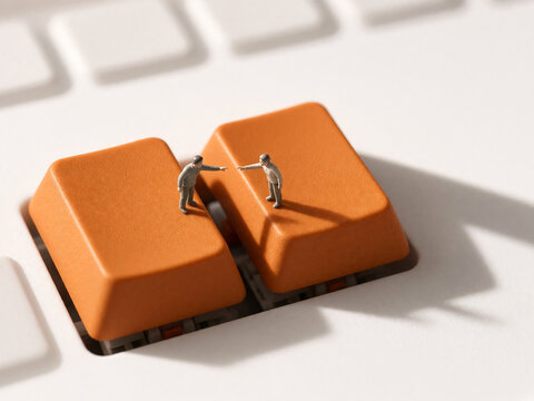 Miniature figures interacting on orange keyboard keys. Conceptual minimalism of office routine and digital communication. Macro photography of tiny people