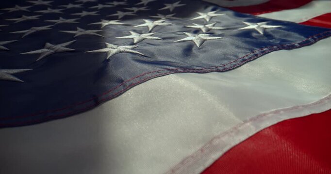 Close-up cinematic shot of the United States flag lying on a horizontal surface under directional local light. Slow push-in camera movement captured with a probe lens and slider.