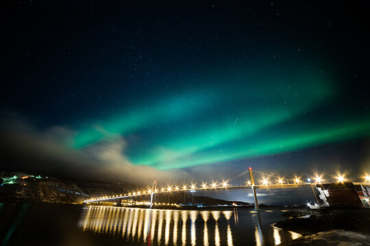 View of the aurora borealis illuminating the night sky above a bridge in Lofoten, Nordland, Norway.